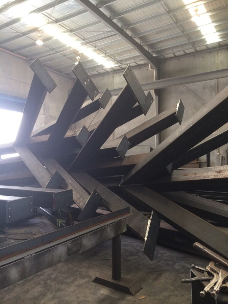 A warehouse containing a large pile of fabricated steel beams.