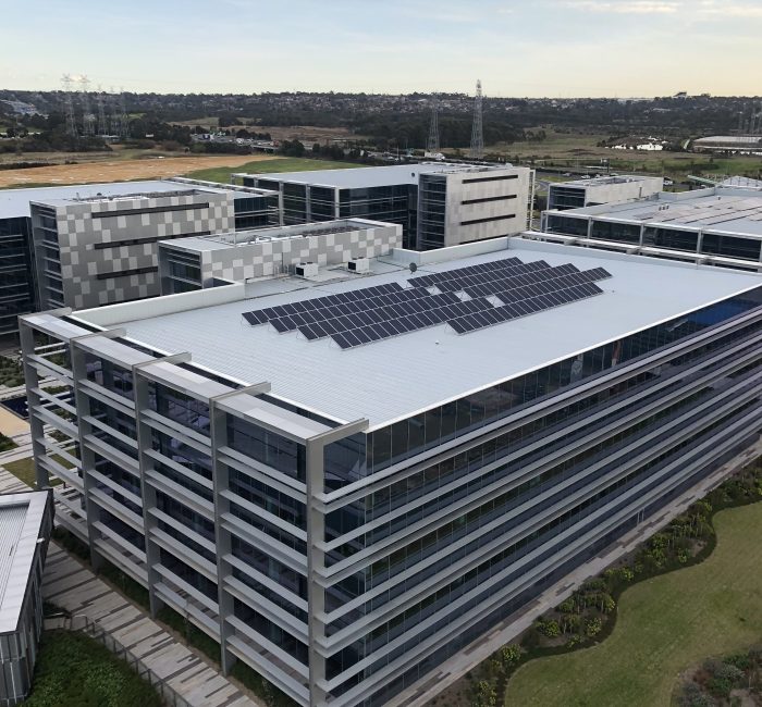 An elevated view of a completed multi-storey glass office building featuring rooftop solar panels